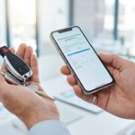 Personne tenant des clés de voiture et un smartphone affichant un formulaire d'assurance provisoire.
