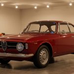 Une élégante Alfa Romeo rouge stationnée dans un garage éclairé, symbole des voitures de collection prisées des voleurs.
